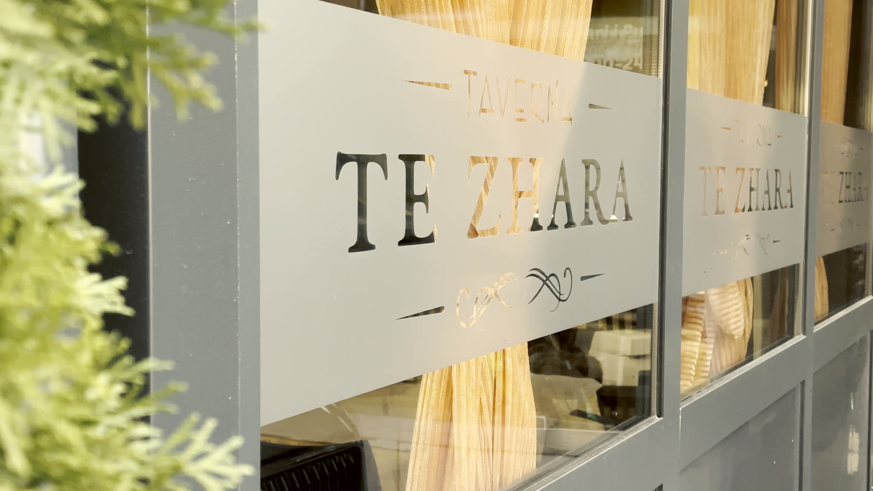 Logoja e Tavernës Zhara në xhamin e hyrjes